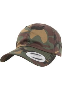 Camo pet met een gebogen rand; gemaakt van stof met groene, bruine en tan patronen. Witte label aan de voorkant met logo van het merk.
