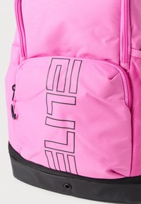 Mochila de nylon rosa con superficie texturizada, que presenta un gran logo negro de "ELITE" y un bolsillo lateral de malla. Base negra para mayor durabilidad.