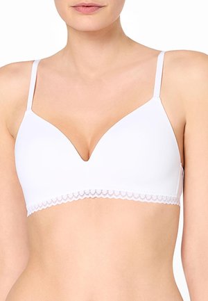 Woman wearing a white bra with thin straps and lace trim along the bottom edge, shown from neck to midriff.