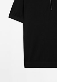 Černá košile s krátkým rukávem vyrobená z měkké tkaniny, s límcem na zip a čistým, minimalistickým designem se rovného střihu.