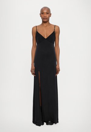 Black, long evening dress with a deep V-neck, fitted bodice, and side slit. Slim spaghetti straps and smooth fabric create a sleek silhouette.