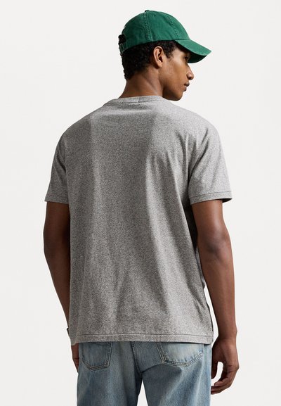 Grijze T-shirt met korte mouwen, een gladde textuur, een ronde halslijn en een relaxte pasvorm, gecombineerd met lichtblauwe denim jeans en een groene pet.