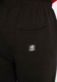 Sorte sweatpants med en myk tekstur, med elastisk midje og en baklomme med et firkantet logo-lapp som viser et hodeskalle-design.
