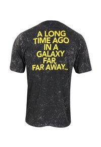 Černé tričko s vintage, poškozenou texturou, na zadní straně s velkým žlutým textem: "PŘED MNOHA A MNOHA LETY V GALAXII DÁLE, DÁLE..."