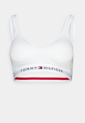 Bralette bianco con spalline sottili e scollo a V. Presenta un elastico con logo e accenti rossi e blu. Texture liscia, stile minimalista.