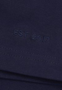 Navy blue cotton fabric with a smooth texture, featuring embroidered text "EST. 2017" in a slightly darker shade at the hem.