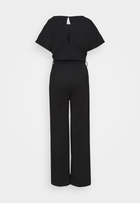 Combinaison noire à manches courtes, jambes larges, dos découpé et taille cintrée avec liens latéraux.