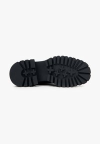 Black rubber sole with deep treads, featuring a rounded toe and rectangular grooves for traction. Durable, flexible texture.