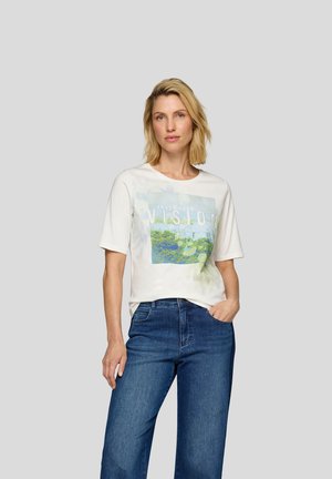 Weißes Kurzarm-T-Shirt mit einem bunten Grafikdruck, der "Vertraue deiner Vision" mit floralen Akzenten zeigt, kombiniert mit blauen weiten Jeans.