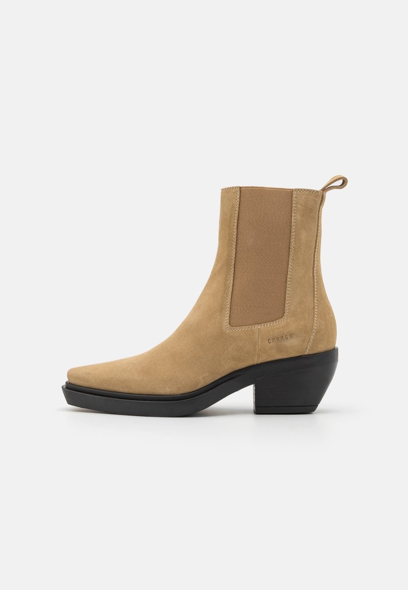 Bottine en daim marron clair avec panneaux latéraux élastiques, talon bloc noir, languette à l'arrière et bout pointu, vue de profil.