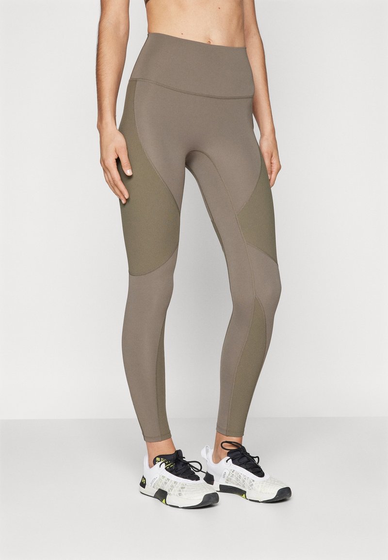 Leggings a vita alta in verde oliva, realizzati in un materiale elasticizzato. Presentano pannelli a coste in contrasto e cuciture sagomate per un look aderente.