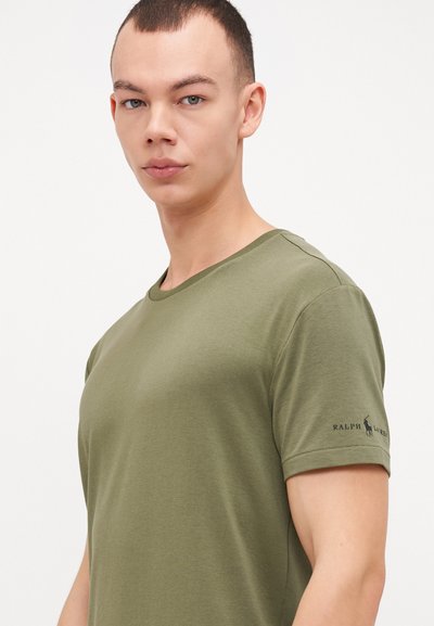T-shirt vert olive en mélange de coton doux, avec un col rond, des manches courtes et un petit logo sur la manche gauche.