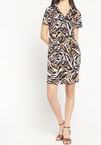 Šaty s krátkým rukávem a límečkem, s úzkým pasem a vícebarevným zebrovaným vzorem v černé, bílé, hnědé a rezavé barvě.