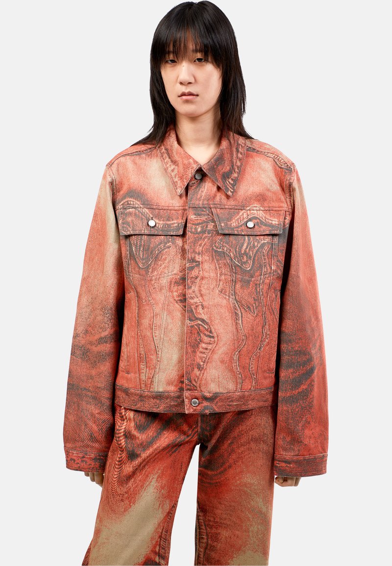Chaqueta de denim con un patrón de mármol en rojo y beige, costuras contrastantes, dos bolsillos en el pecho y un diseño de cuello clásico.