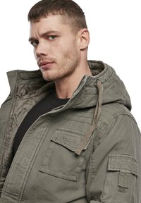 Olivgrüne Kapuzenjacke mit Reißverschluss, ausgestattet mit Fronttaschen, strukturiertem Stoff und verstellbarem Zugband an der Kapuze.