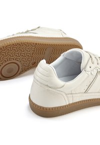 White leather shoes with a textured surface, round toe, and rubber sole featuring a zigzag pattern. Laces and eyelets included.