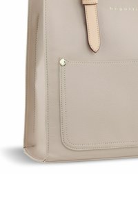 Sac tote en cuir beige avec une finition texturée, doté d'une poche avant avec un bouton-pression doré et d'une sangle assortie en brun clair. Accents de design simples.