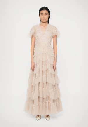 Robe longue en tulle rose doux, à niveaux superposés avec des couches froncées, un décolleté en V profond et de courtes manches bouffantes. La jupe descend jusqu'au sol, offrant un aspect texturé.