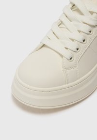Weiße Sneaker mit einem glatten Leder-Obermaterial, runder Zehenform, flachen Schnürsenkeln und minimalistischem Design. Besitzt kontrastierende Nähte und eine dicke Sohle.