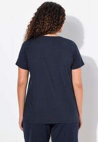 Marineblå T-shirt med korte ærmer lavet af blødt stof. Rund halsudskæring og en løs pasform, med synlige sømdetaljer på bagsiden.