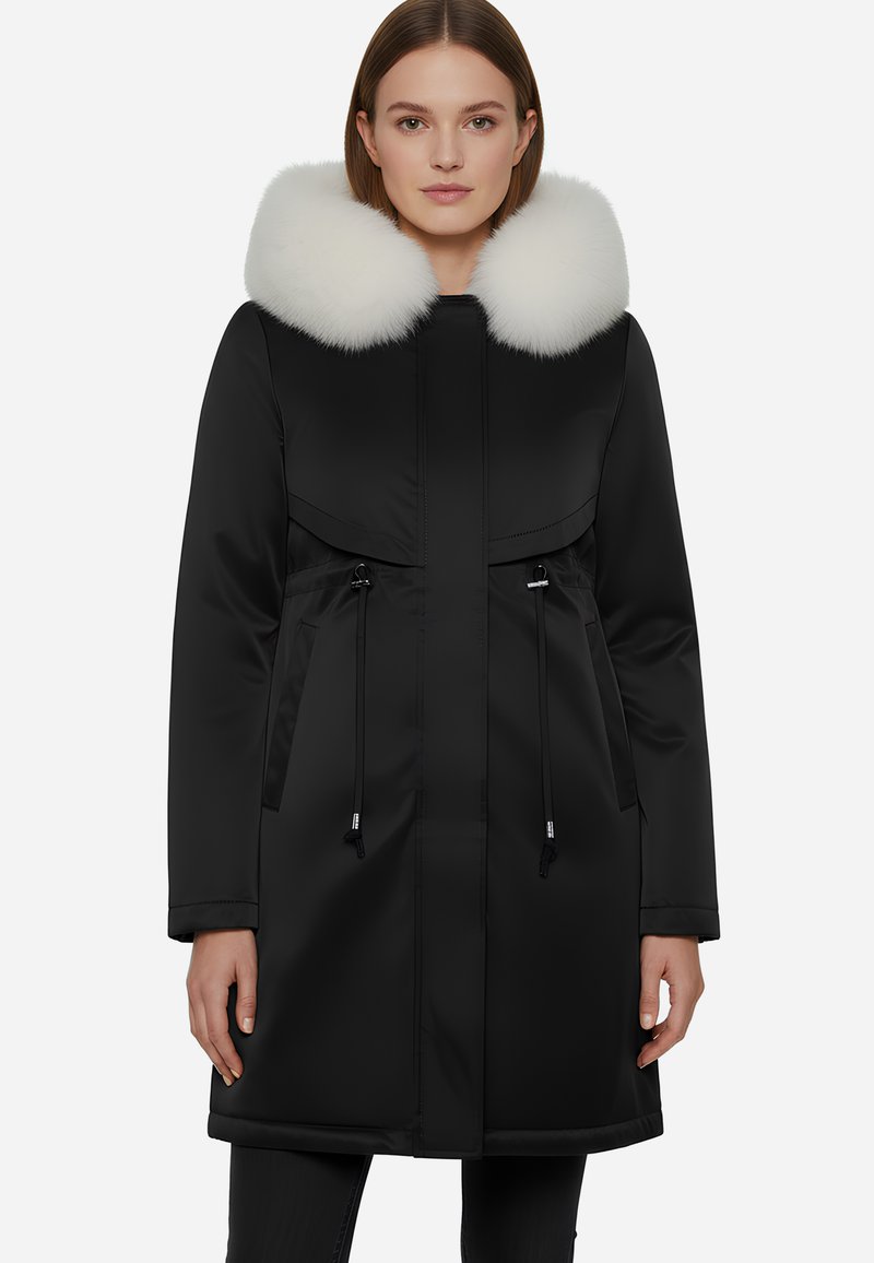 Parka nera con colletto in pelliccia bianca, dotata di zip frontale, cordini regolabili e due tasche laterali. Tessuto liscio e resistente all'acqua.