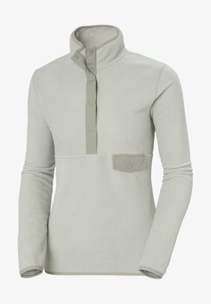 Sudadera de felpa gris claro con cuello alto, cierre de presión en la parte delantera y un pequeño bolsillo en el pecho con un botón. Textura suave y lisa.