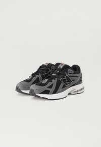 Chaussures de sport noires et grises avec tige en mesh, semelle rembourrée et système de lacets. Comprend un logo de marque et des accents réfléchissants.