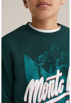 Sweatshirt vert avec un graphique de montagne en vert foncé, texte blanc et rouge "Monte" et un col rond côtelé.
