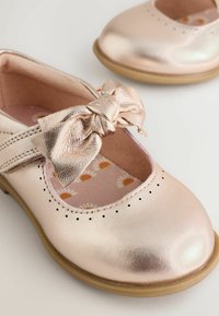 Metalen roze leren schoenen met een ronde neus en een decoratieve strik. Voorzien van stikseldetails, perforaties en een binnenzool met bloemenpatroon.