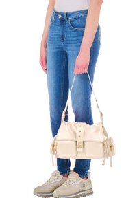 Borsa a mano in pelle crema con un design strutturato, dotata di due tasche frontali, chiusura a scatto e accessori in tono oro, tenuta da una persona che indossa jeans blu.