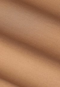 Beige stof met een gladde textuur, met subtiele diagonale ribbels, die een uniforme kleur over het materiaal toont.