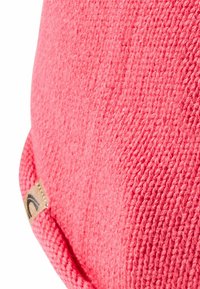 Roze gebreide stof met een gestructureerd oppervlak en afgeronde vorm. Bevat een klein label met een embleem dat aan de zijkant is bevestigd.