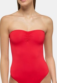 Costume da bagno intero rosso senza spalline con dettaglio arricciato sul seno, texture liscia e aperture delle gambe a taglio alto.