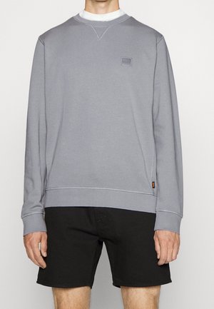 Felpa grigia con maniche lunghe, scollo rotondo e dettaglio con logo ricamato. Abbina a pantaloncini neri. Tessuto liscio e vestibilità casual.