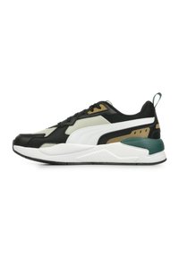 Svart och vit atletisk sneaker med strukturerade material, gröna och gyllene detaljer, lagerdesign och en vadderad sula.