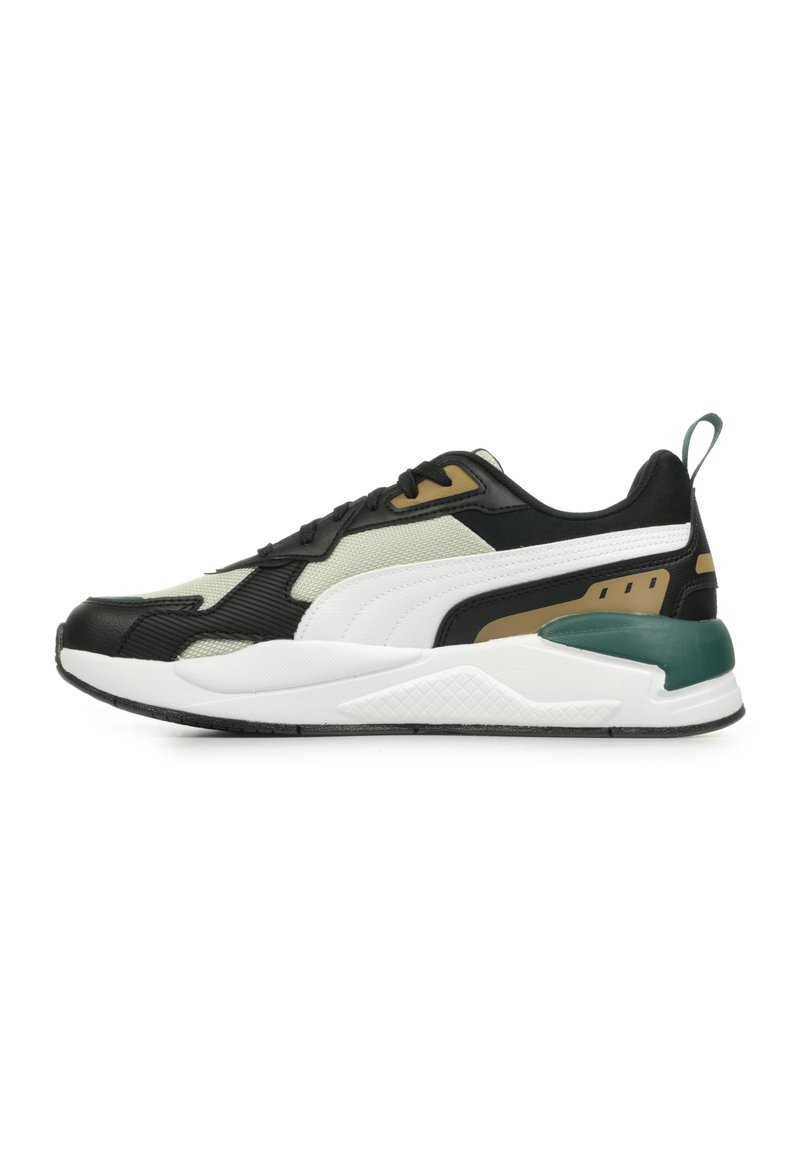 Svart och vit atletisk sneaker med strukturerade material, gröna och gyllene detaljer, lagerdesign och en vadderad sula.