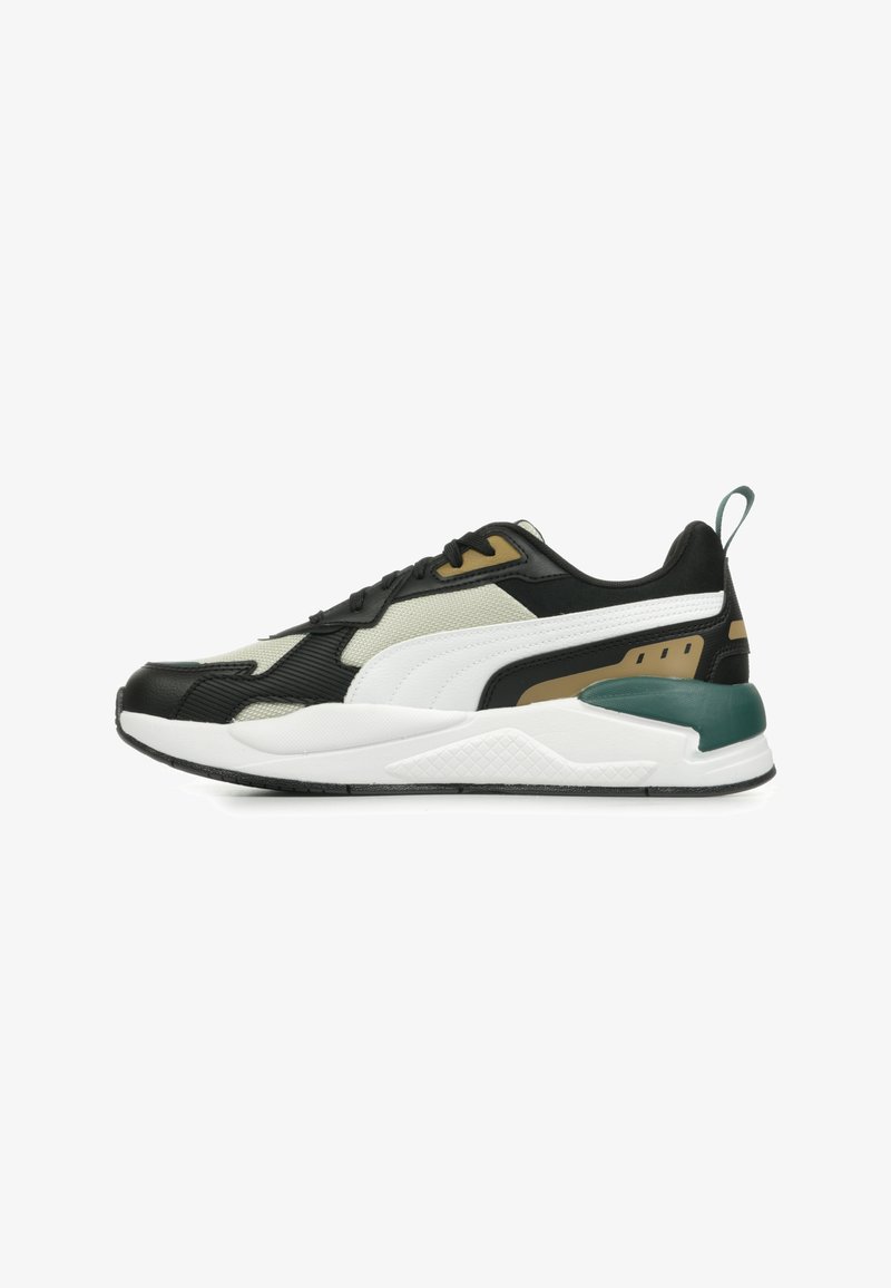 Svart och vit atletisk sneaker med strukturerade material, gröna och gyllene detaljer, lagerdesign och en vadderad sula.