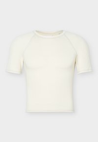 Κοντομάνικο, εφαρμοστό κρεμ crop top με στρογγυλή λαιμόκοψη και raglan ραφές, εμφανίζεται σε απλό φωτεινό φόντο.