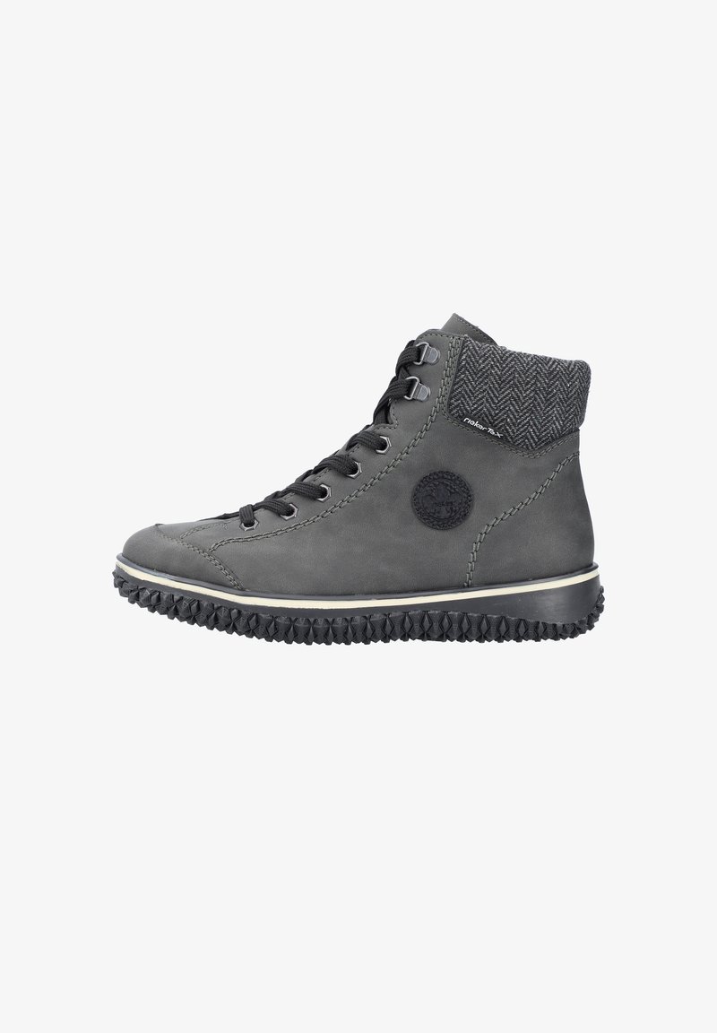 Chaussure mi-montante en cuir gris avec semelle en caoutchouc noire texturée, dotée d'un col en tissu à chevrons et de lacets noirs. Logo circulaire sur le côté.