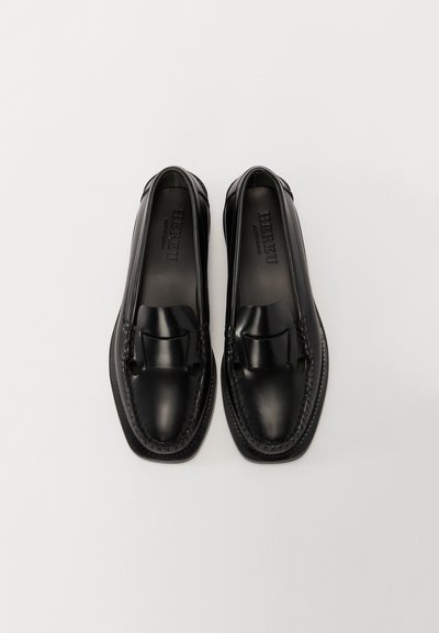 Mocassins en cuir noir avec un panneau avant surélevé, un détail tissé sur les côtés, et un design de bout lisse et arrondi.