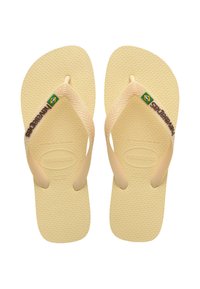 Tongs en caoutchouc beige avec un semelage texturé, des fines lanières et un logo vert et jaune. Taille 37-38 imprimée sur les semelles.