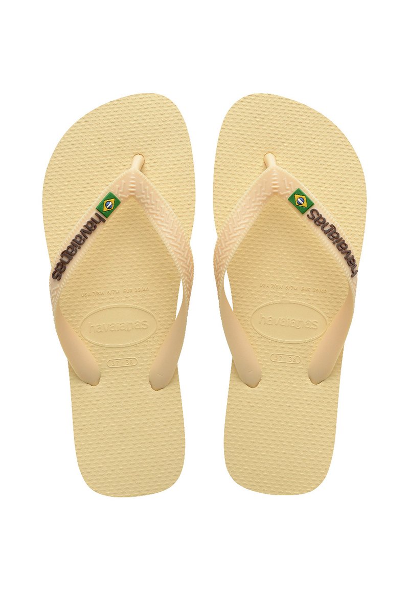 Tongs en caoutchouc beige avec un semelage texturé, des fines lanières et un logo vert et jaune. Taille 37-38 imprimée sur les semelles.