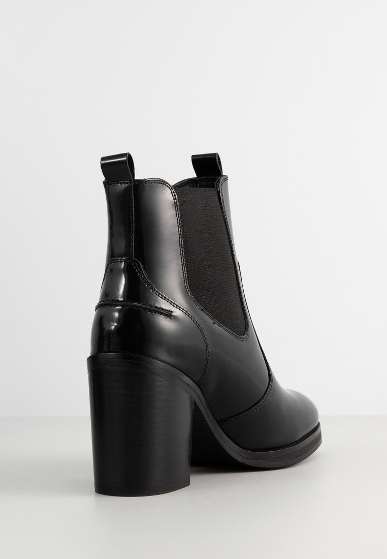 Schwarze Leder-Stiefelette mit runder Zehenpartie, elastischen Seitenpaneelen und einem klobigen hohen Absatz. Hat eine glatte Oberfläche und minimale Nähte.