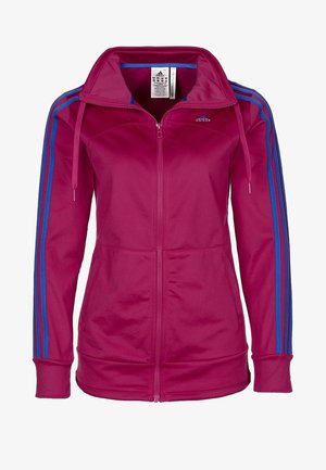 Magentanvärinen Adidas-vetoketjullinen verryttelytakki sinisillä kolmiraidallisilla yksityiskohdilla hihoissa ja pystypääntiellä.