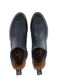 Para czarnych i granatowych skórzanych butów typu slip-on z detalami brogów i tanowym wnętrzem, widziana z góry.