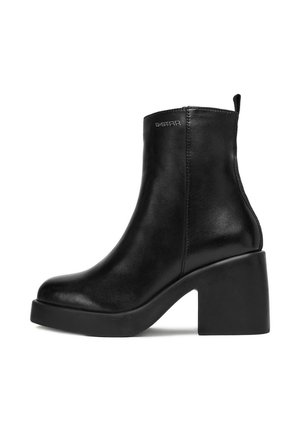Stivaletto in pelle nera con tacco spesso, punta rotonda e logo G-Star vicino alla cima, su uno sfondo bianco.