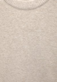 Gros plan sur un tissu tricoté côtelé beige clair avec un col montant, montrant une texture douce et confortable.