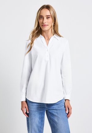 Witte langlopende shirt met een kraag en knoopsluiting, met een gladde textuur en een relaxte pasvorm, in combinatie met lichtblauwe jeans.