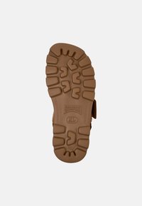 Brown rubber shoe sole with textured grip design, featuring raised patterns and the brand "Camper" logo. Size marked as 38.