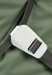 Zielony pasek materiałowy z srebrną metalową klamrą, posiadający prostokątny wycięcie zaprojektowane do zabezpieczania paska wokół przedmiotu.